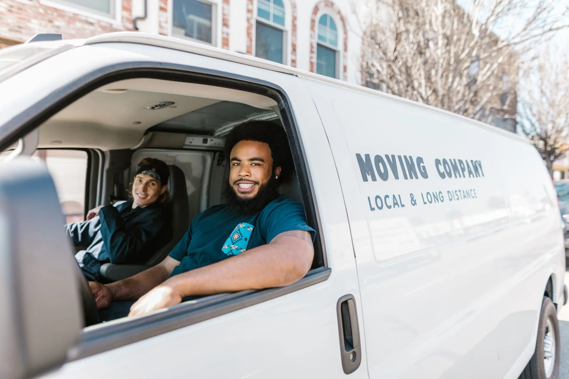 Two movers smiling from their moving company van